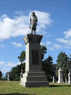 A statue of a person on a pedestal in a cemeteryDescription automatically generated with medium confidence
